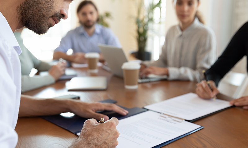 Three office workers sit around a table