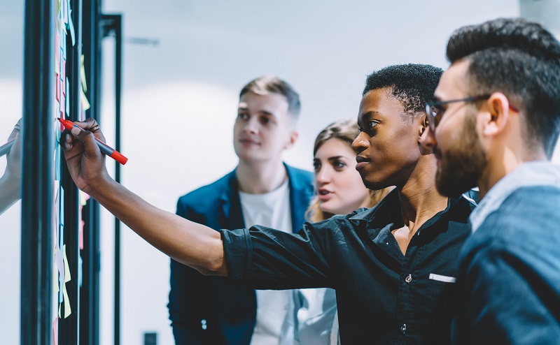 Four young professionals surround a white board